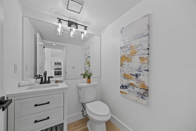 bathroom with baseboards, vanity, toilet, and wood finished floors