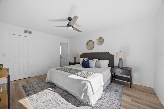 bedroom with a ceiling fan, visible vents, baseboards, and wood finished floors