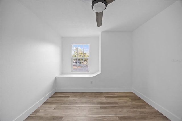 empty room featuring light wood finished floors, a ceiling fan, and baseboards