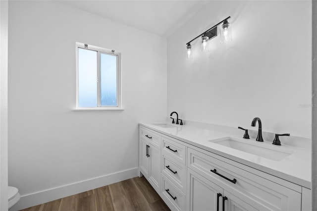 full bathroom with toilet, a sink, baseboards, and wood finished floors