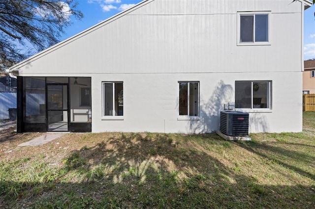 back of house with a sunroom, central AC, a lawn, and fence