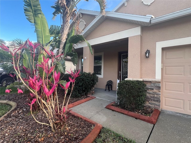 entrance to property with a garage and stucco siding