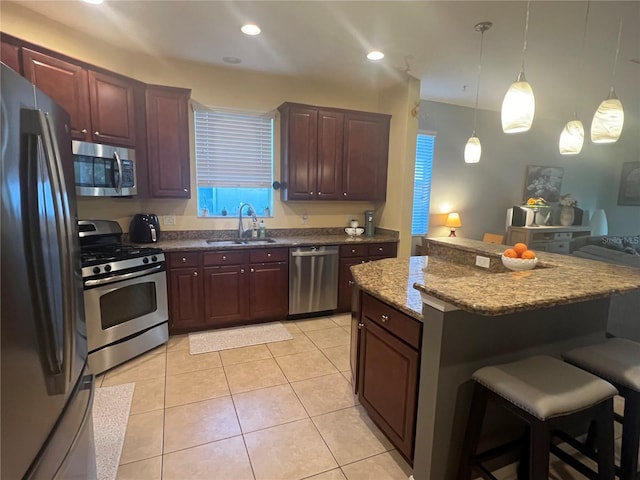 kitchen with a kitchen breakfast bar, decorative light fixtures, stainless steel appliances, a sink, and light tile patterned flooring