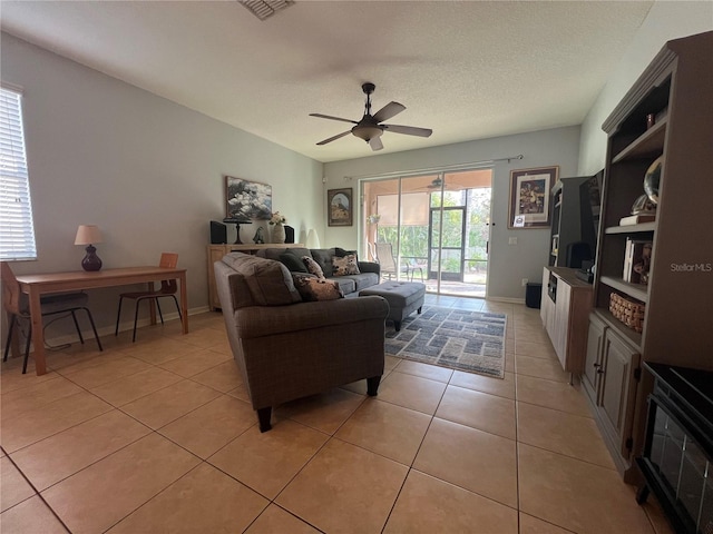 living area featuring light tile patterned floors, ceiling fan, a textured ceiling, and visible vents