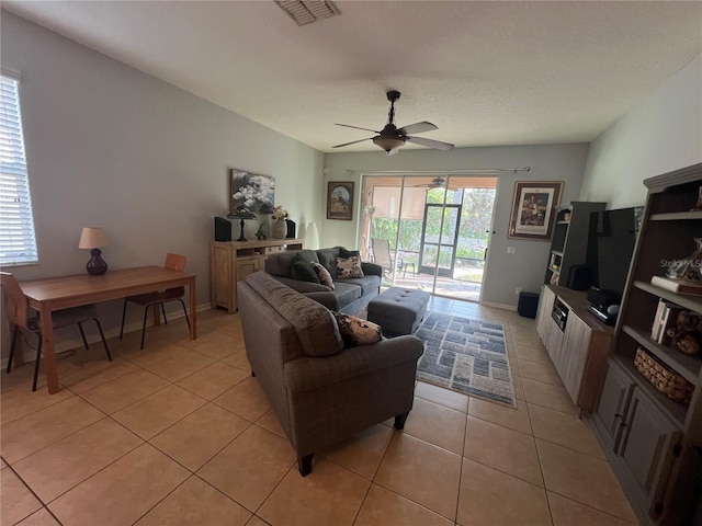 living room with light tile patterned floors, baseboards, visible vents, and a ceiling fan