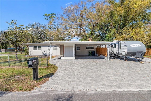 view of front of house with a carport, decorative driveway, and fence