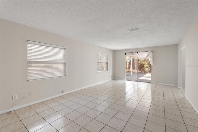 spare room with visible vents, a textured ceiling, baseboards, and light tile patterned flooring