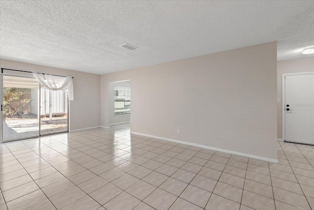 spare room featuring visible vents, light tile patterned floors, a wealth of natural light, and baseboards