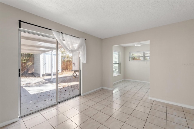 spare room with plenty of natural light, a textured ceiling, and light tile patterned floors