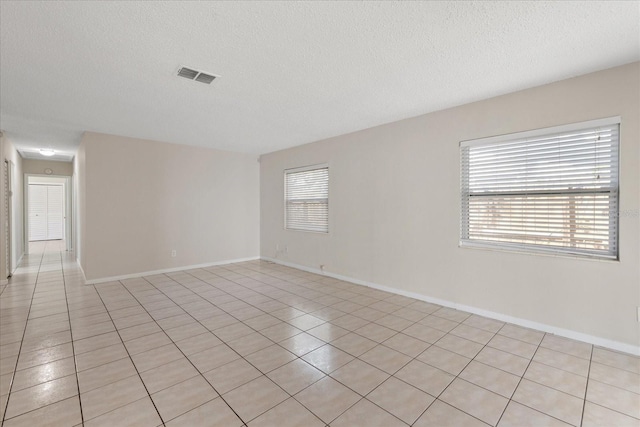 unfurnished room with a textured ceiling, visible vents, and baseboards