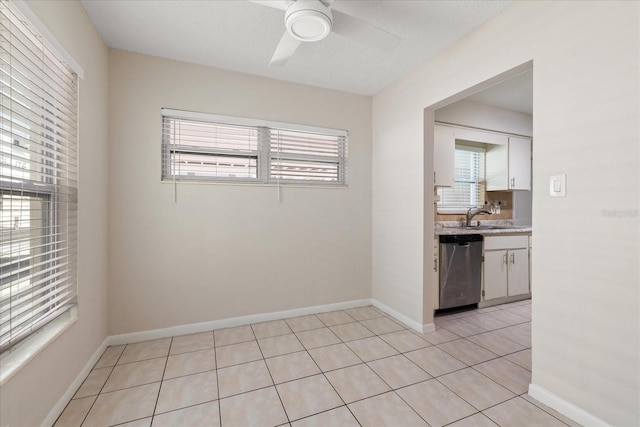 spare room featuring light tile patterned floors, ceiling fan, baseboards, and a sink