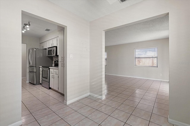 interior space featuring a textured ceiling, baseboards, and light tile patterned floors