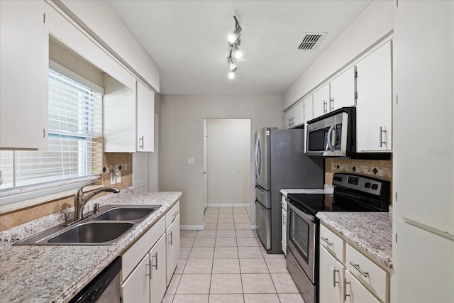 kitchen featuring appliances with stainless steel finishes, a sink, white cabinets, and decorative backsplash