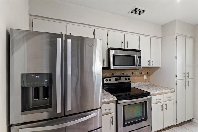 kitchen featuring light stone counters, visible vents, backsplash, appliances with stainless steel finishes, and white cabinetry