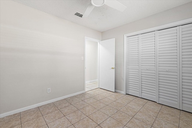 unfurnished bedroom with light tile patterned floors, baseboards, visible vents, a textured ceiling, and a closet