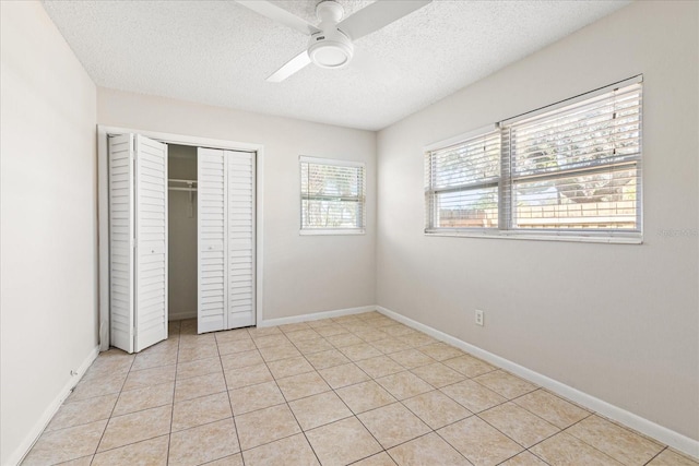 unfurnished bedroom with a closet, a textured ceiling, and baseboards