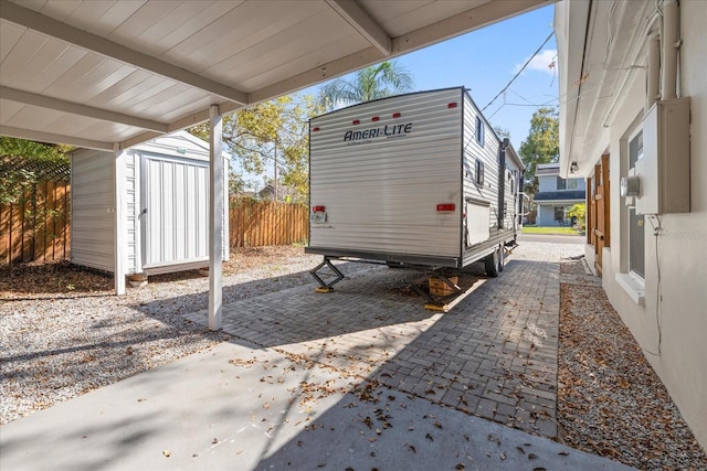 view of parking featuring fence and a shed