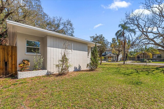 view of side of home featuring a lawn and fence