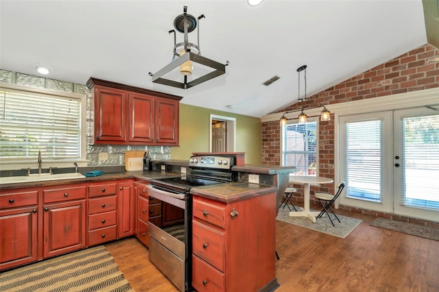 kitchen with electric range, visible vents, lofted ceiling, a peninsula, and a sink