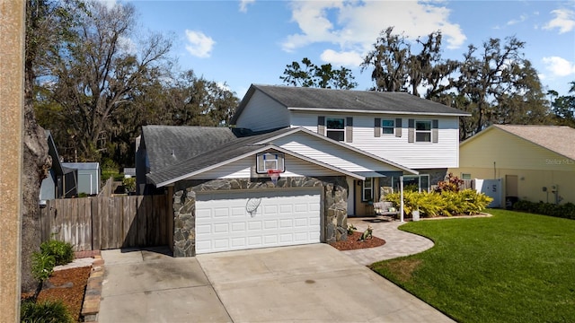 view of front of home with an attached garage, fence, stone siding, driveway, and a front yard