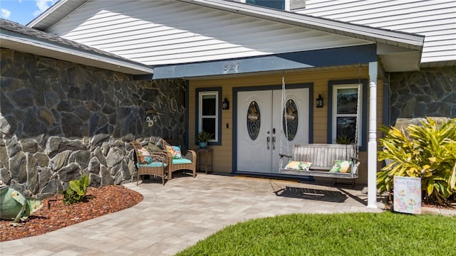 doorway to property with stone siding and a porch