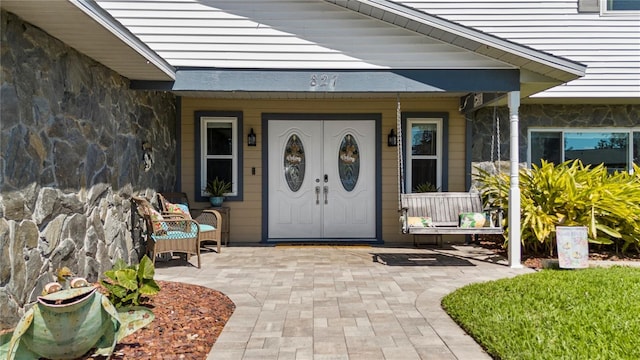 doorway to property with stone siding and covered porch