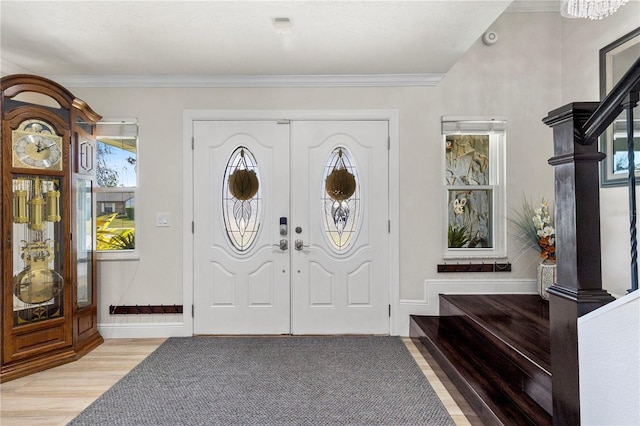 foyer entrance featuring light wood-type flooring, stairs, crown molding, and french doors