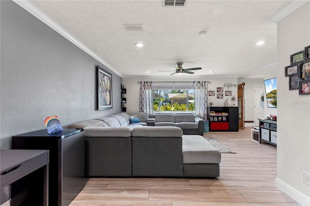 living area with a textured wall, crown molding, and light wood finished floors