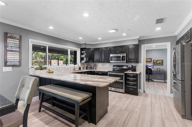 kitchen with light stone counters, stainless steel appliances, a peninsula, visible vents, and tasteful backsplash