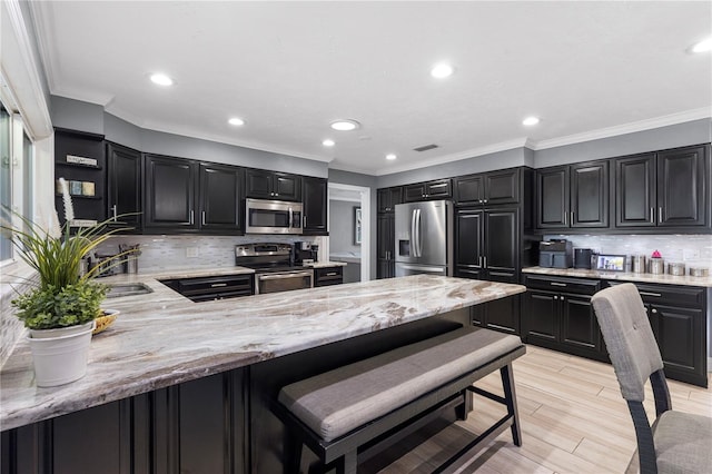 kitchen with appliances with stainless steel finishes, a sink, dark cabinetry, and light stone countertops