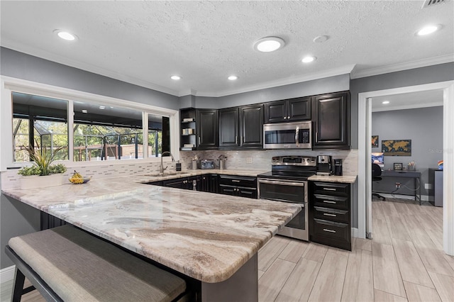 kitchen featuring light stone counters, a breakfast bar area, stainless steel appliances, a peninsula, and backsplash