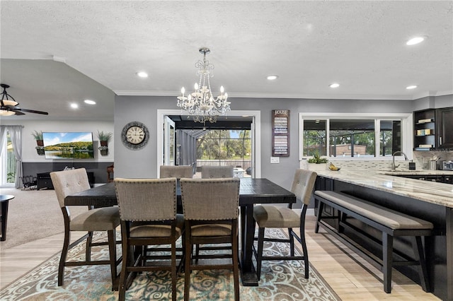 dining area with ornamental molding, light wood-style floors, and a textured ceiling