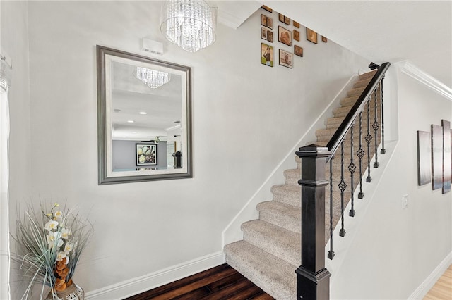 stairway featuring baseboards, a chandelier, and wood finished floors