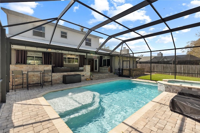 view of pool with glass enclosure, a pool with connected hot tub, outdoor dry bar, and a patio