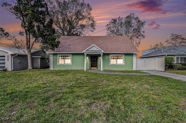 view of front of home featuring a lawn, fence, a gate, and stucco siding