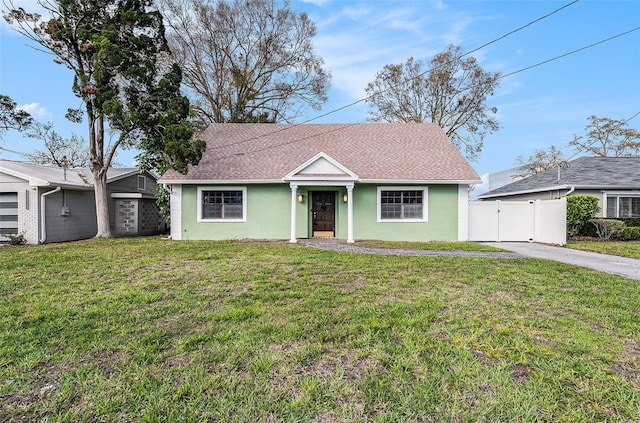 view of front facade with fence, roof with shingles, a gate, stucco siding, and a front yard