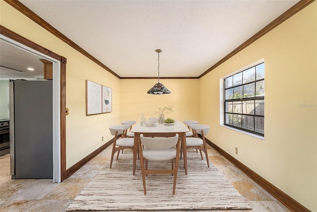 dining room with a textured ceiling, ornamental molding, and baseboards