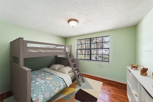 bedroom featuring a textured ceiling, baseboards, and wood finished floors