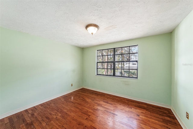 unfurnished room featuring a textured ceiling, wood finished floors, and baseboards