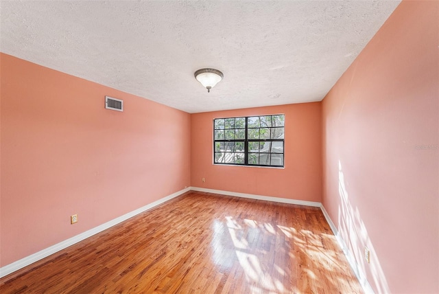 unfurnished room featuring wood finished floors, visible vents, and baseboards