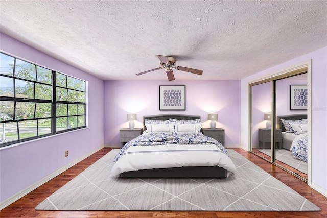 bedroom featuring a closet, ceiling fan, a textured ceiling, wood finished floors, and baseboards