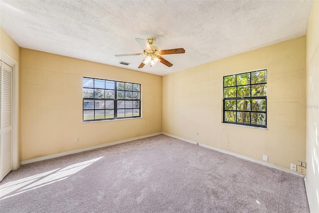 spare room with ceiling fan, a textured ceiling, visible vents, and carpet flooring