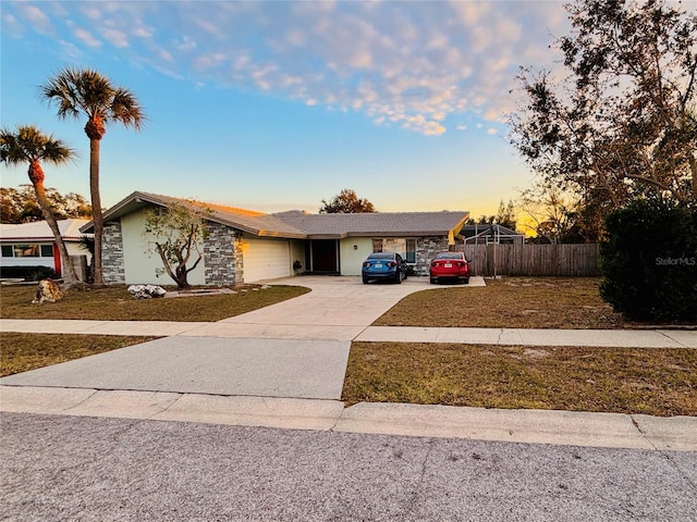 view of front of house with a garage, concrete driveway, stone siding, and fence