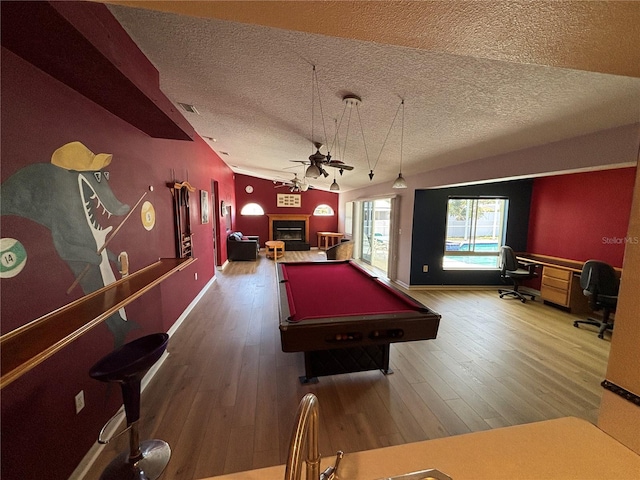 playroom with visible vents, a ceiling fan, wood finished floors, a textured ceiling, and a fireplace