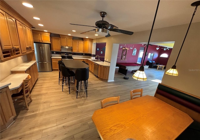 kitchen featuring brown cabinets, light wood-type flooring, stainless steel appliances, and a sink