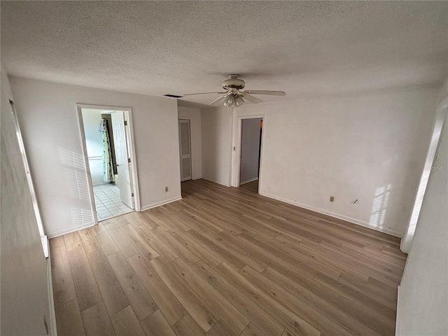 unfurnished bedroom with baseboards, visible vents, ceiling fan, wood finished floors, and a textured ceiling