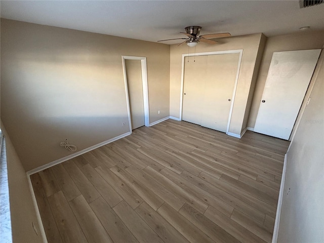 unfurnished bedroom featuring a closet, visible vents, ceiling fan, wood finished floors, and baseboards