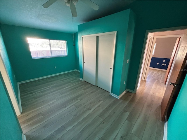 unfurnished bedroom featuring ceiling fan, a closet, wood finished floors, and baseboards