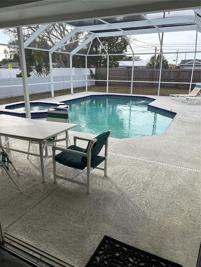 view of swimming pool with glass enclosure, a patio area, a fenced backyard, and a pool with connected hot tub