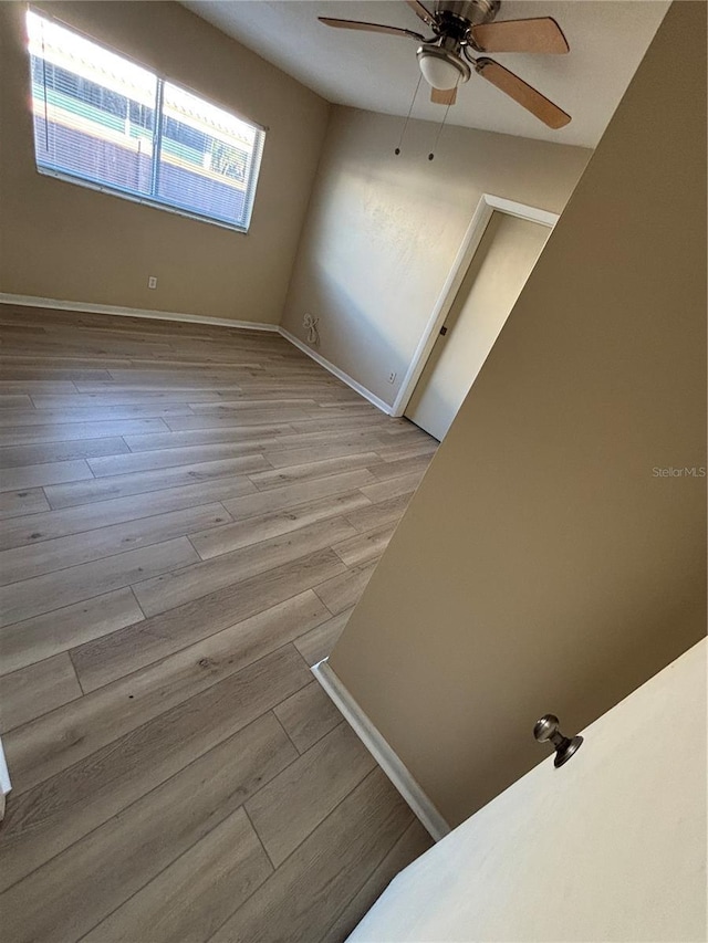 empty room featuring ceiling fan, wood finished floors, and baseboards